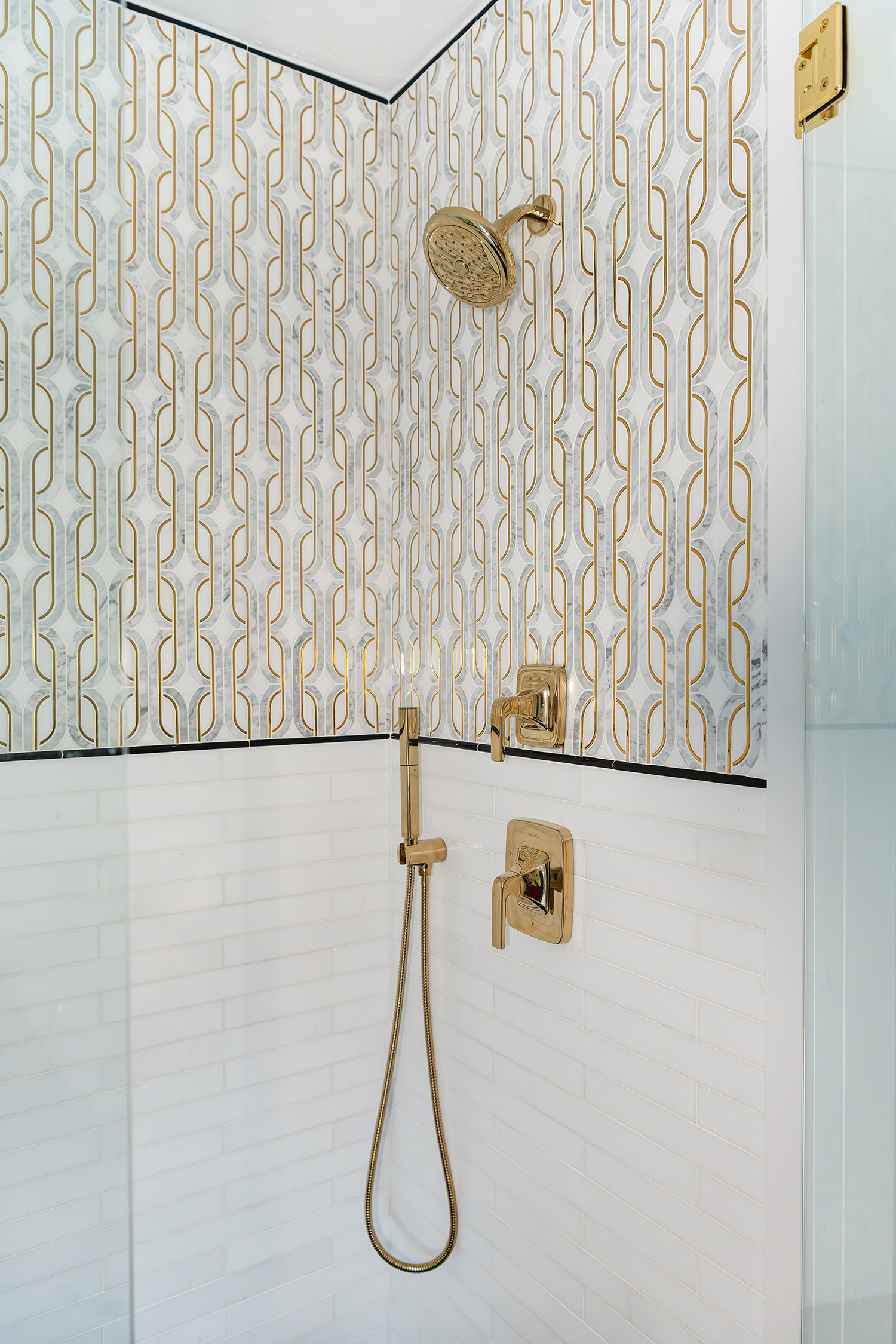 Custom white and gold tiling in a shower of a bathroom remodel by Marlene & Co